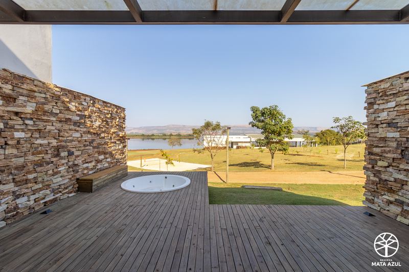 Deck do loft, entre muros de pedra, com a represa ao fundo