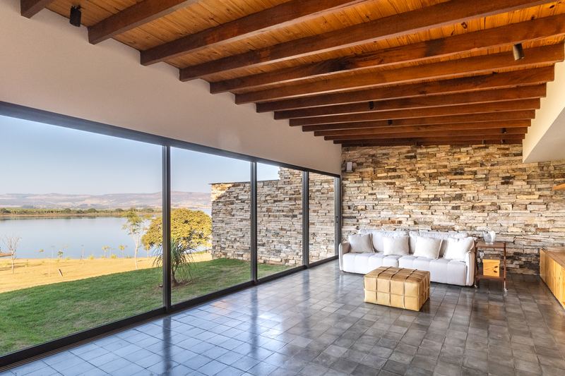 Sala de estar de uma casa com parede de pedra e vista para a água